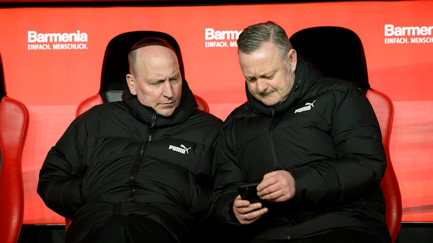 Roland Virkus und Stephan Schippers schauen auf ein Smartphone.