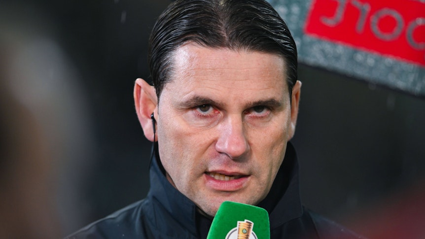Trainer von Borussia Mönchengladbach spricht in ein Mikrofon.