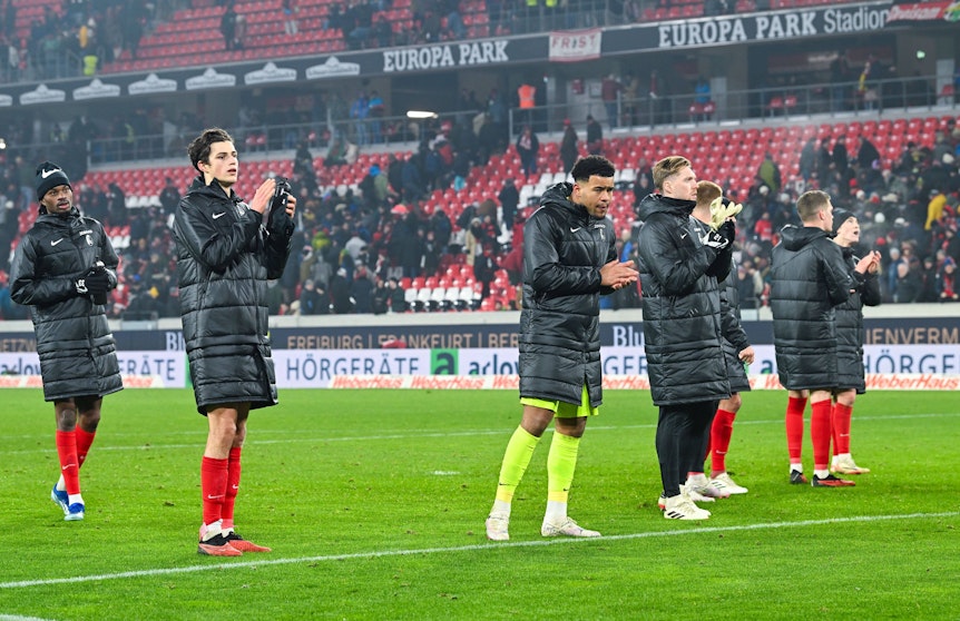 Spieler des SC Freiburg vor der Fankurve.