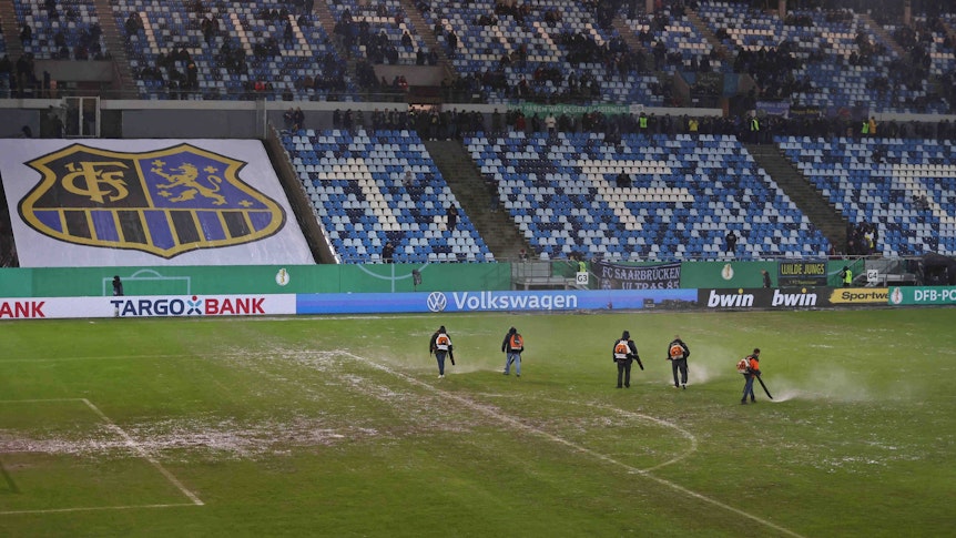 Helferinnen und Helfer mit Laubbläser auf dem Rasen im Ludwigsparkstadion.