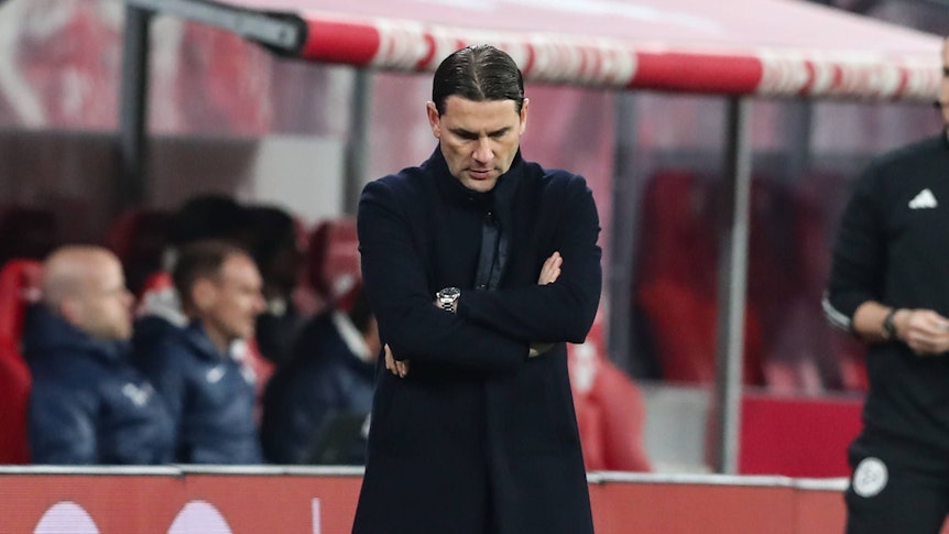 Trainer von Borussia Mönchengladbach verschränkt die Arme und schaut auf den Boden.