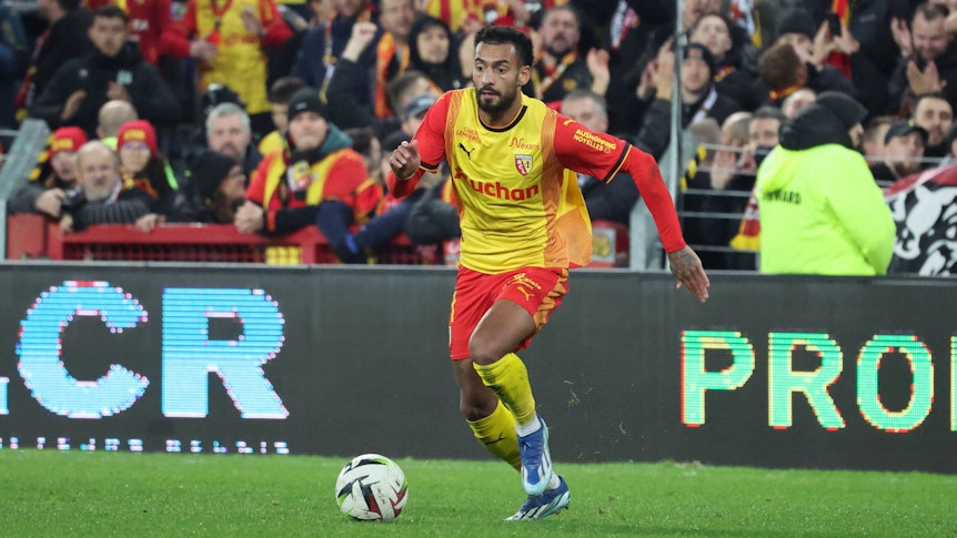Angelo Fulgini dribbelt mit dem Ball im gelben Lens-Trikot.