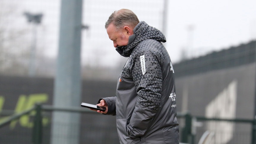Roland Virkus schaut auf sein Smartphone.