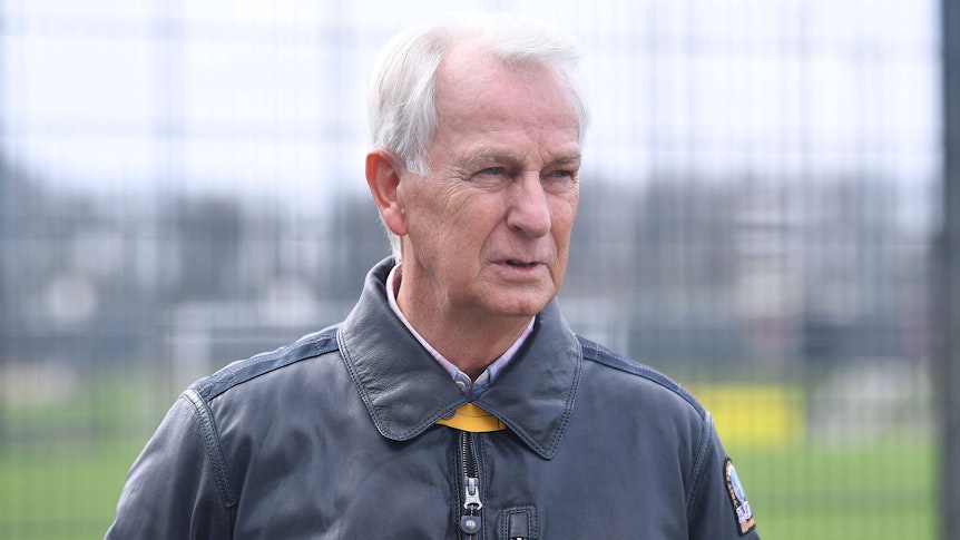 Rainer Bonhof mit fokussiertem Blick in einer Lederjacke am Trainingsplatz.