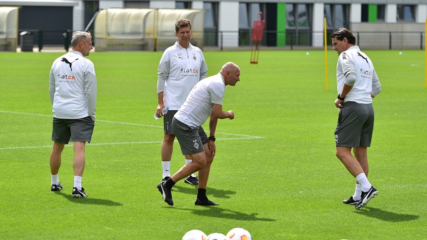 Vier Gladbach-Trainer auf dem Platz. Oliver Neuville greift sich ans Knie.