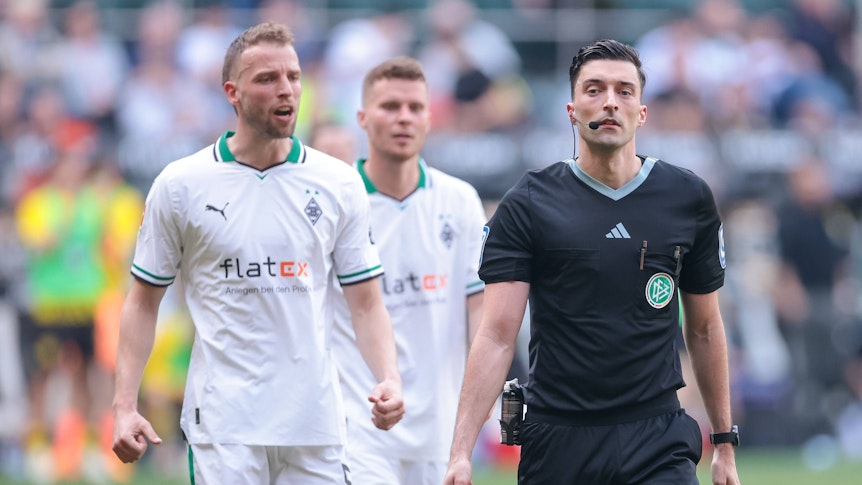 Schiedsrichter bei einem Spiel von Borussia Mönchengladbach. Im Hintergrund Marvin Friedrich und Nico Elvedi.