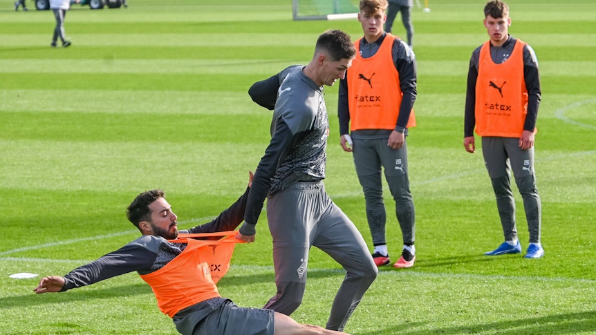 Lukas Ullrich und Luca Netz schauen zu, während sich Tomas Cvancara und Jacob Italiano im Borussia-Training duellieren.