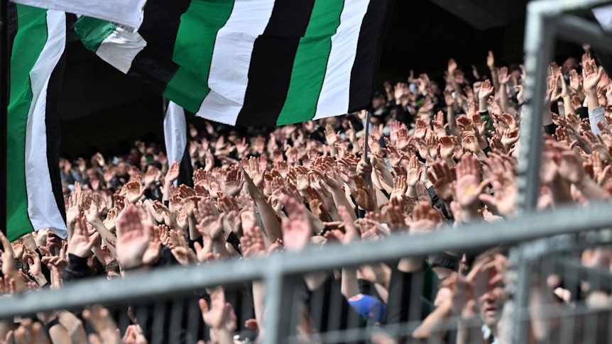 Borussia-Fans in der Nordkurve reißen die Hände nach oben.
