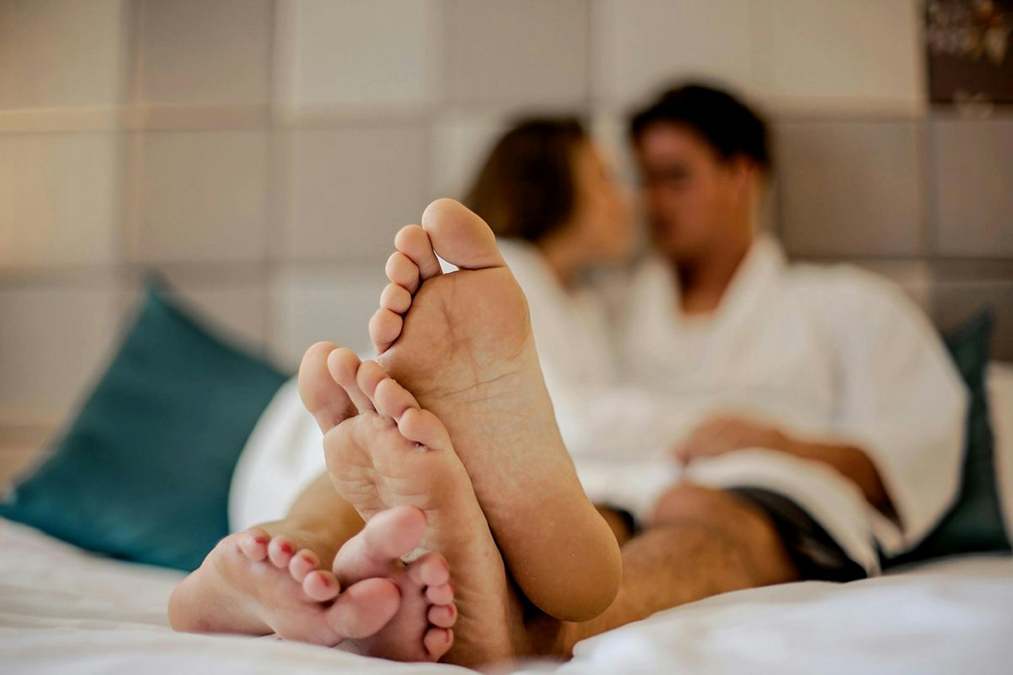 Paar im Bett mit ausgestreckten Füßen