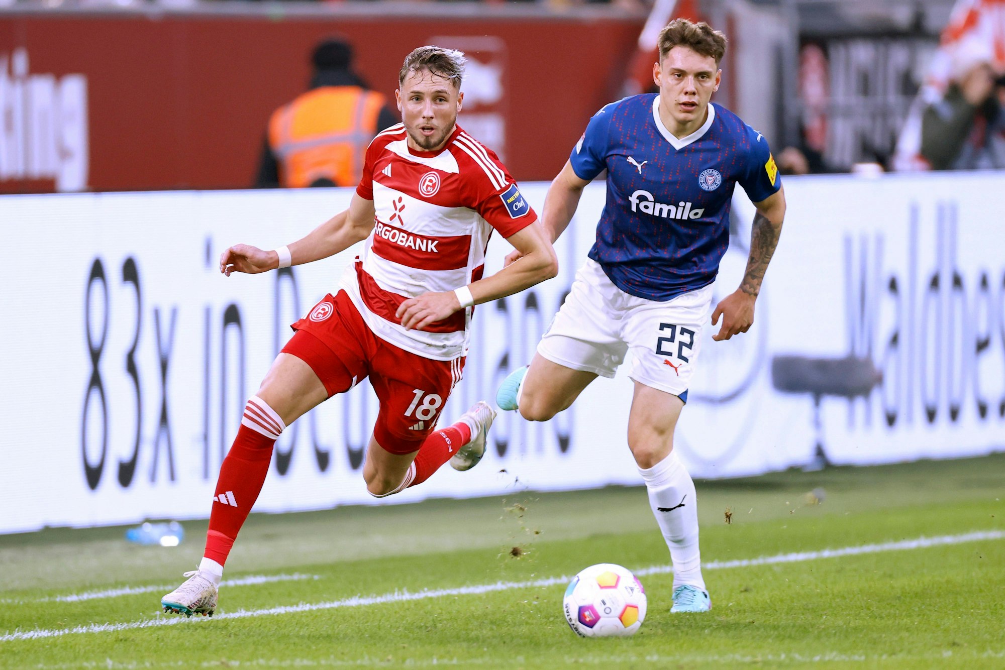 Fortuna Düsseldorfs Jona Niemiec und Kiels Nicolai Remberg blicken dem Ball hinterher.