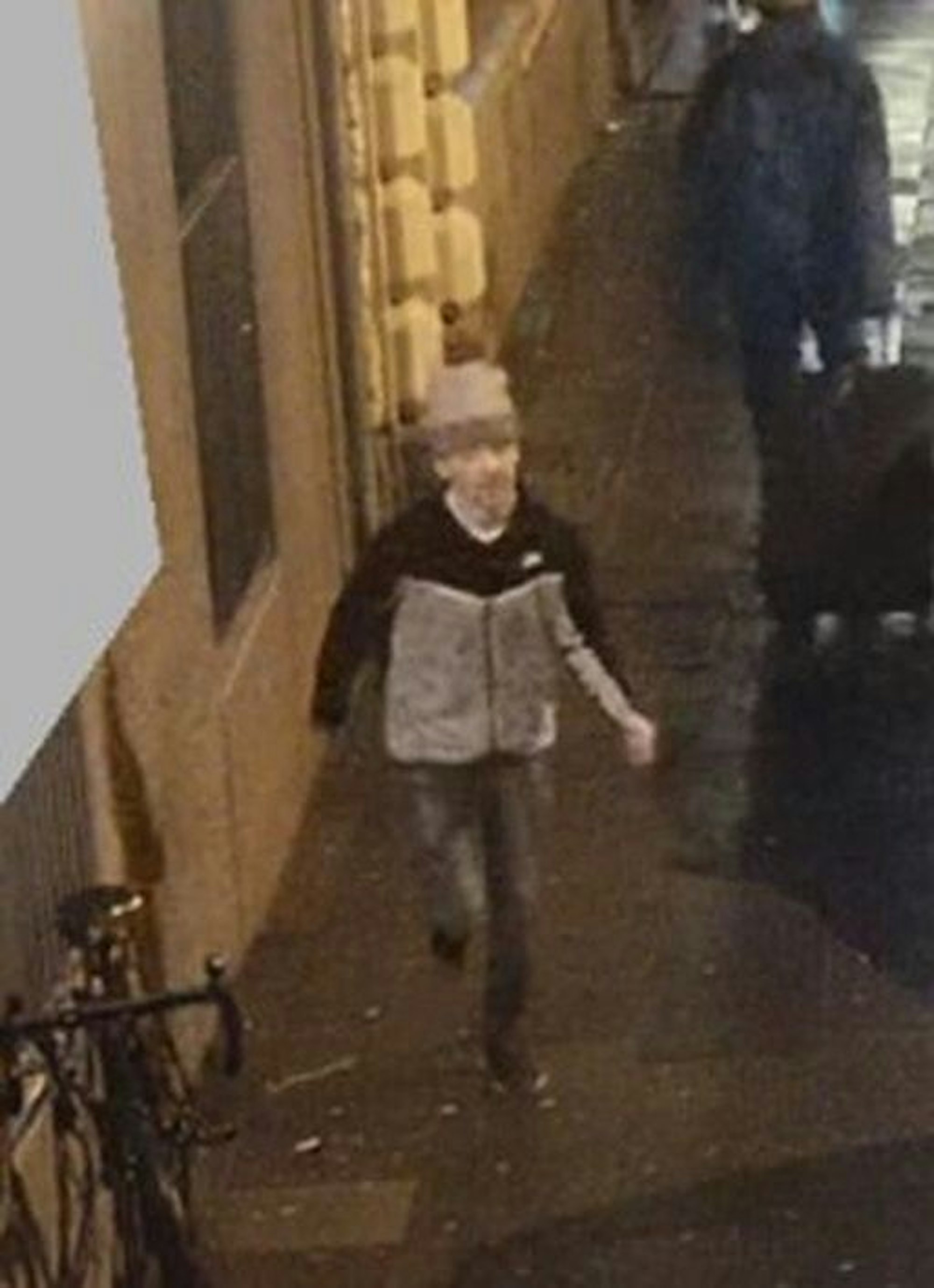 Mann in grauer Jacke auf einem Fahndungsbild. Er läuft durch eine Straße.