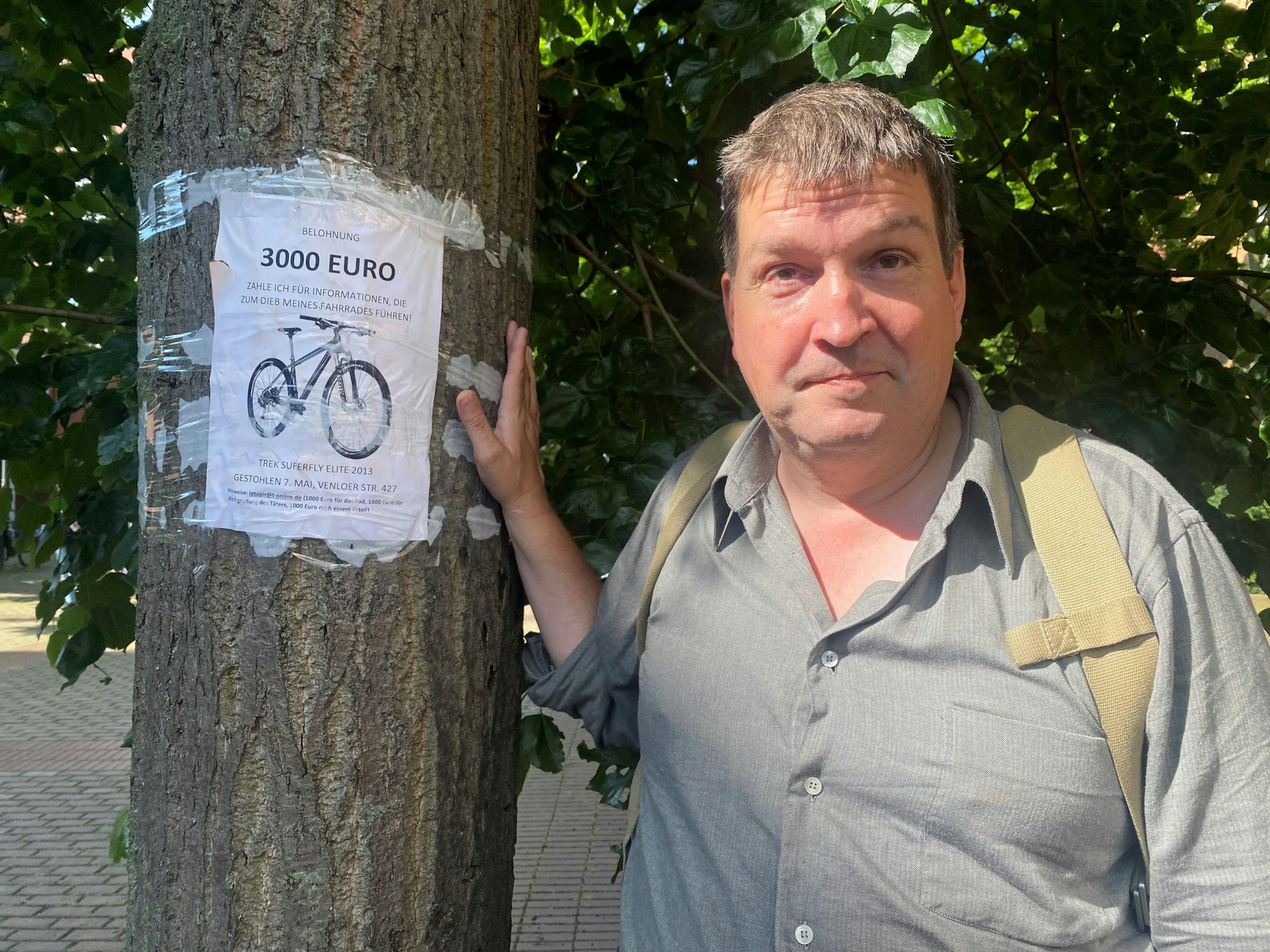 Kay Meiners steht vor einem Baum, auf den er das Mini-Plakat mit dem Hinweis auf 3000 Euro Belohnung geklebt hat.