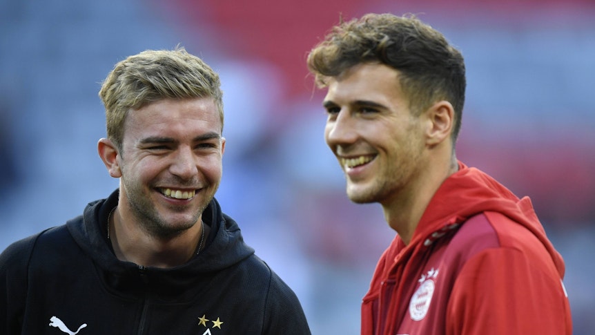 Borussia Mönchengladbachs Christoph Kramer und Bayerns Leon Goretzka stehen gemeinsam lachend auf dem Platz.