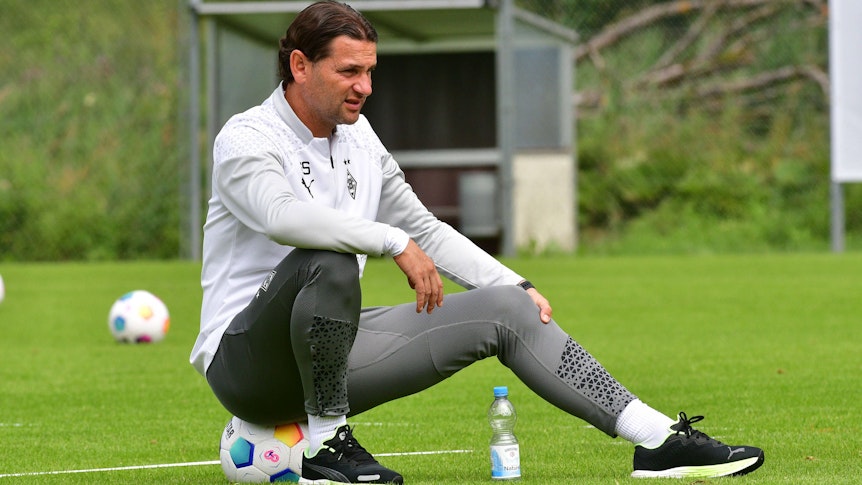 Borussia Mönchengladbachs Trainer Gerardo Seoane sitzt auf einem Ball und beobachtet die Trainingseinheit.
