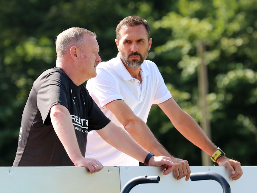 Martin Stranzl und Roland Virkus stehen beim Training von Borussia Mönchengladbach neben dem Platz und unterhalten sich.