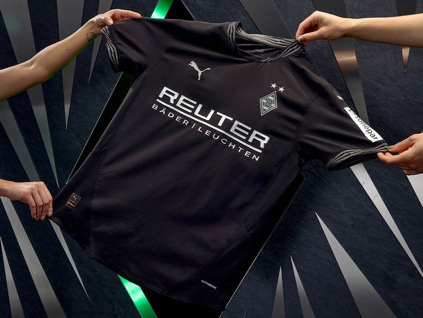 Vier Hände präsentieren das neue Ausweich-Trikot von Borussia Mönchengladbach.