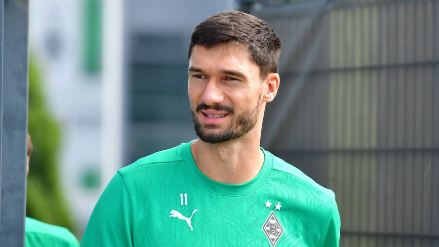 Borussia Mönchengladbachs Tim Kleindienst läuft auf den Trainingsplatz und lächelt in die Kamera.