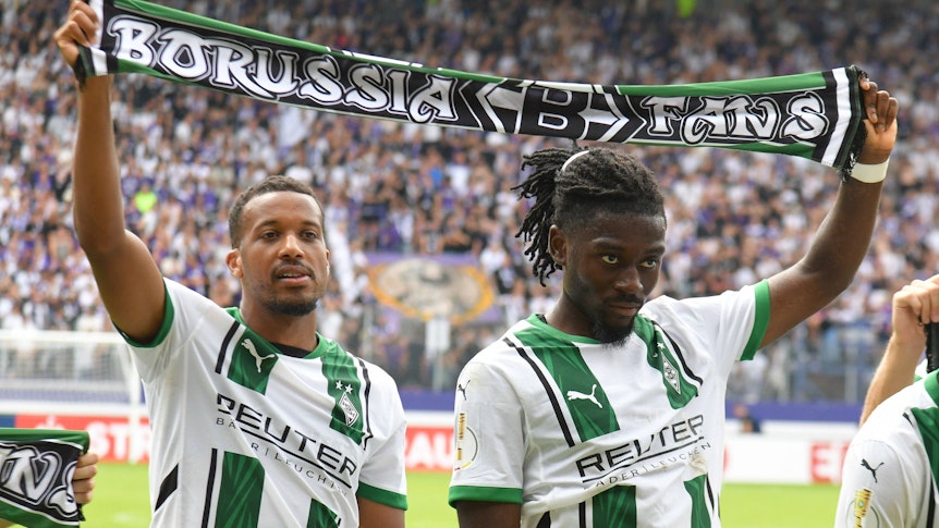 Alassane Plea und Manu Koné halten einen Schal in der Hand.