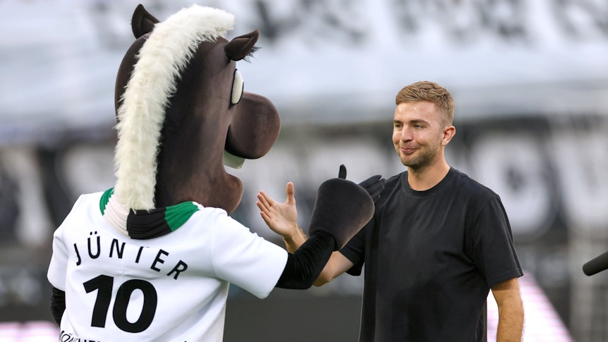 Christoph Kramer schlägt mit dem Maskottchen von Borussia Mönchengladbach ein.