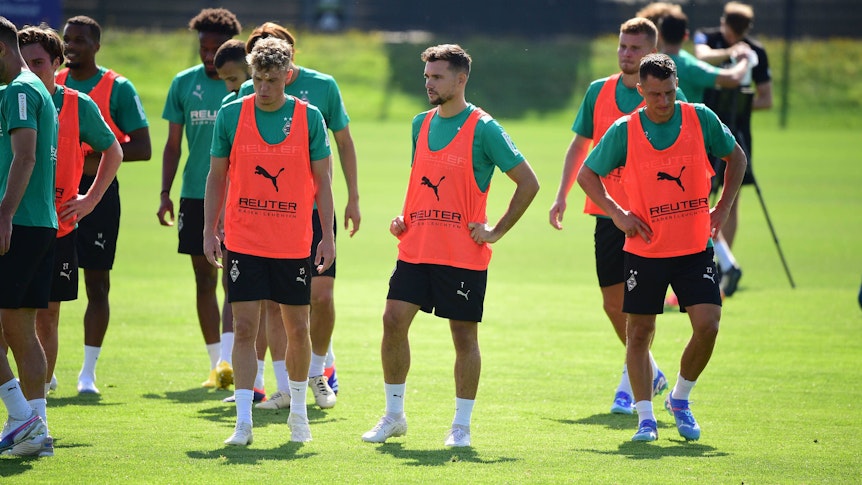 Die Gladbach-Profis Robin Hack, Kevin Stöger und Stefan Lainer stehen nebeneinander auf dem Trainingsplatz und schnaufen durch.
