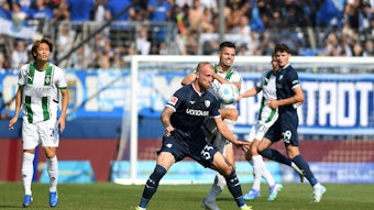 Bochums Philipp Hofmann und Borussia Mönchengladbachs Julian Weigl kämpfen um den Ball, Ko Itakura schaut aus dem Hintergrund auf die Szene.