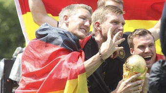 Bastian Schweinsteiger, Per Mertesacker und Kevin Grokreutz juben mit dem Weltmeister-Pokal.