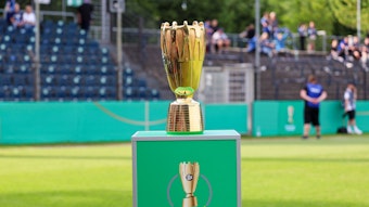 Der goldene DFB-Pokal der Junioren auf einem grünen Sockel.