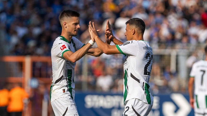 Die Gladbach-Profis Julian Weigl und Stefan Lainer klatschen im Spiel beim VfL Bochum auf dem Platz ab.