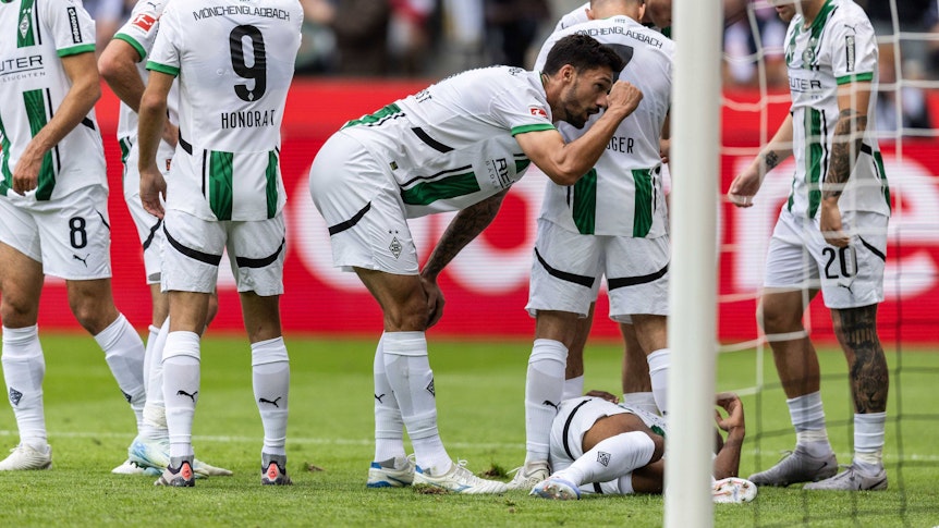 Borussia Mönchengladbachs Alassane Plea liegt im Bundesliga-Spiel gegen den VfB Stuttgart verletzt am Boden, seine Teamkollegen stehen daneben.
