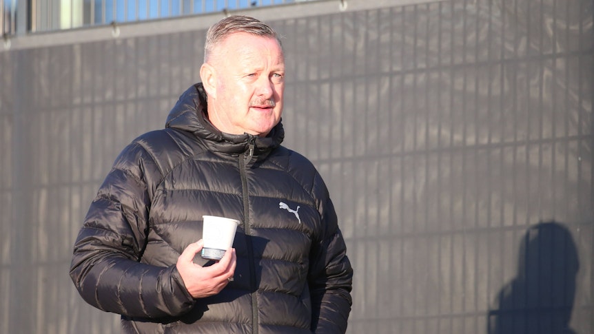 Roland Virkus auf dem Trainingsgelände mit einem Becher Kaffee.