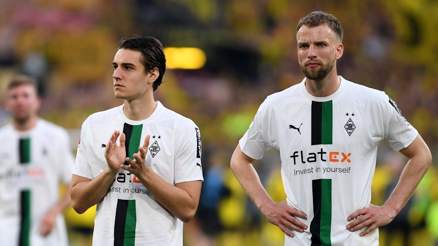 Die Gladbach-Profis Florian Neuhaus und Marvin Friedrich stehen nach dem Spiel bei Borussia Dortmund vor der Fankurve und blicken enttäuscht.