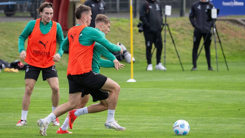 Borussia Mönchengladbachs Philipp Sander kämpft im Training mit Niklas Swider um den Ball. Im Hintergrund beobachtet Rocco Reitz die Szene.