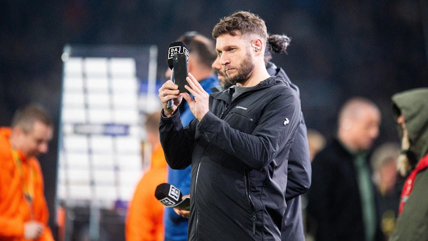 Moritz Volz im Einsatz für DAZN macht ein Foto mit seinem Handy.