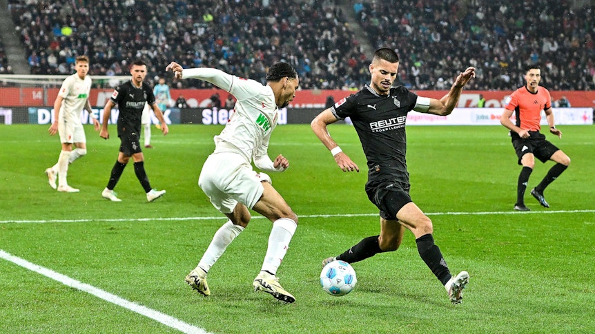 Alexis Claude-Maurice uit Augsburg en Julian Weigl van Borussia Mönchengladbach strijden om het bal.