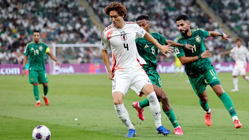 Ko Itakura behauptet den Ball gegen zwei Gegenspieler im Nationaltrikot.