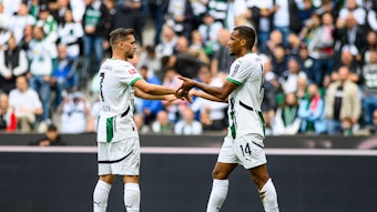 Kevin Stöger und Alassane Plea klatschen sich auf dem Spielfeld ab.