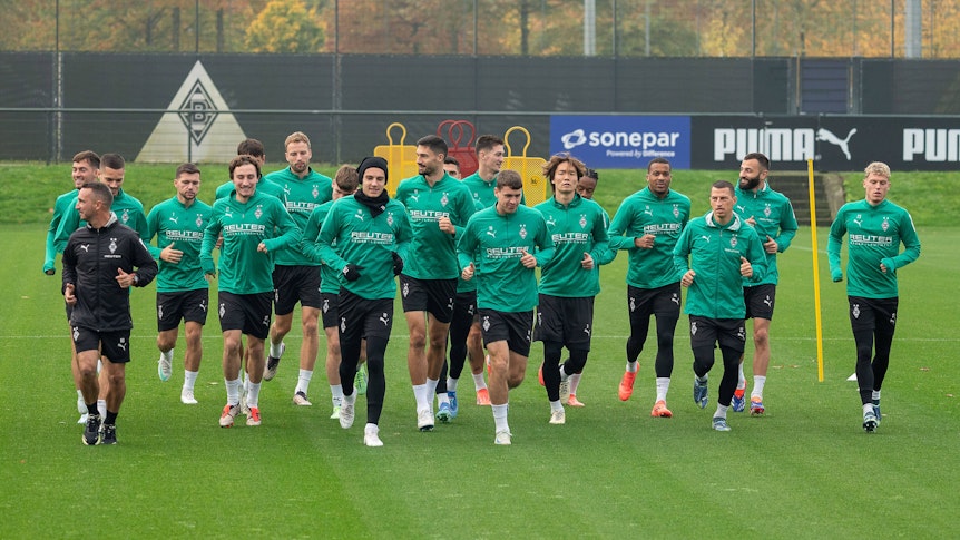 Die Spieler von Borussia Mönchengladbach wärmen sich gemeinsam auf dem Trainingsplatz auf.