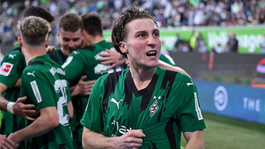 Rocco Reitz greift sich ins Trikot und schaut jubelnd zu den Fans hoch.
