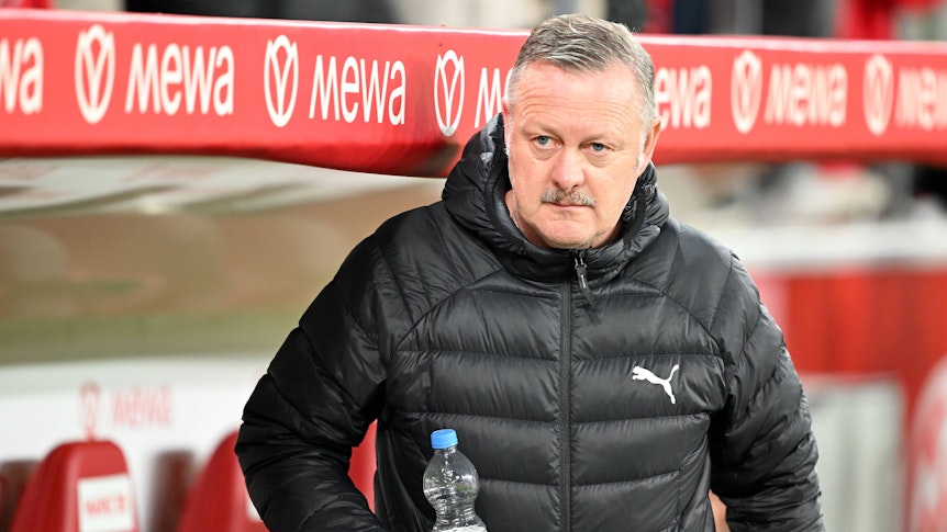 Roland Virkus beim Spiel in Mainz auf der Trainerbank mit einer Wasserflasche in der Hand.