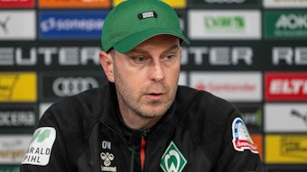 Werder Bremens Trainer Ole Werner sitzt auf dem Podium und spricht bei der Pressekonferenz.