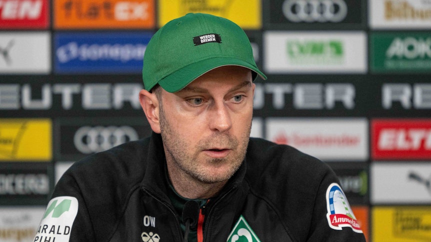 Werder Bremens Trainer Ole Werner sitzt auf dem Podium und spricht auf der Pressekonferenz.