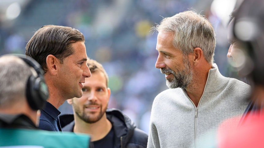 Marco Rose und Gerardo Seoane im Profil gegenüberstehend. Beide lächeln.