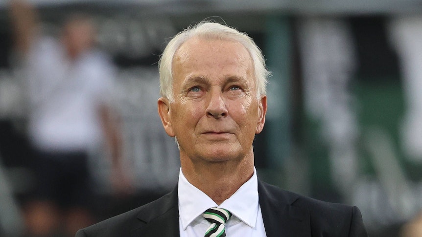 Borussia Mönchengladbachs Präsident Rainer Bonhof steht beim Bundesliga-Spiel gegen Bayer leverkusen in der Arena und blickt auf die Tribüne.