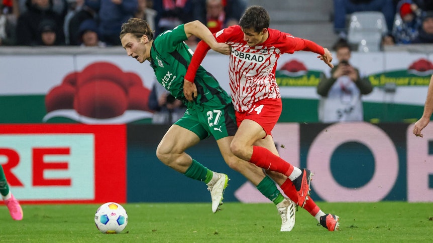 Borussia Mönchengladbachs Rocco Reitz kämpft mit Freiburgs Merlin Röhl um den Ball.
