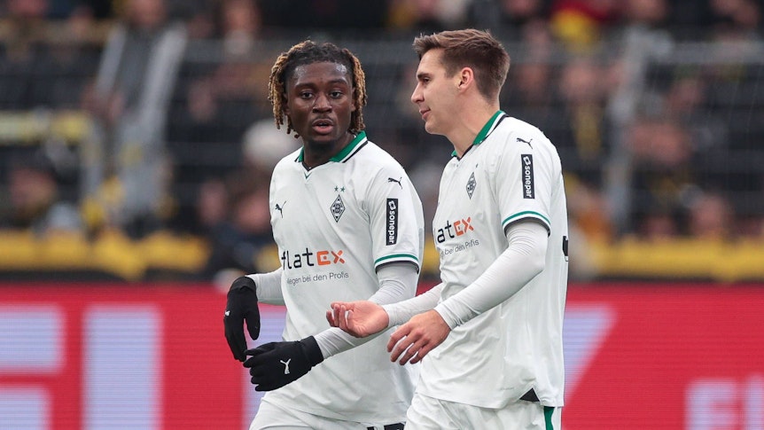 Die Gladbach-Profis Manu Koné und Maximilian Wöber laufen beim Auswärtsspiel gegen Borussia Dortmund nebeneinander über den Platz und unterhalten sich.
