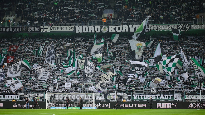 Die Fans von Borussia Mönchengladbach schwenken in der Nordkurve beim Bundesliga-Spiel gegen Holstein Kiel ihre Fahnen.