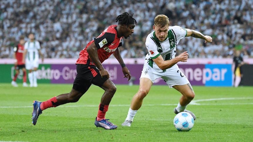Bayer Leverkusens Jeremie Frimpong geht im Zeikampf an Borussia Mönchengladbachs Luca Netz vorbei.