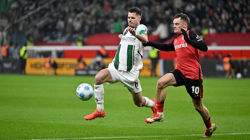 Bayer Leverkusens Florian Wirtz und Borussia Mönchengladbachs Julian Weigl kämpfen um den Ball.
