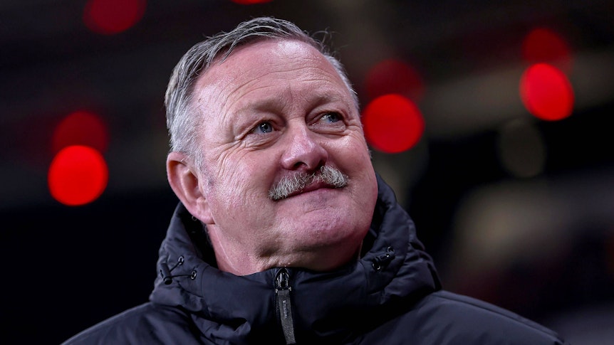 Borussia Mönchengladbachs Sport-Geschäftsführer Roland Virkus steht beim Spiel in Leverkusen im Stadion und lächelt.