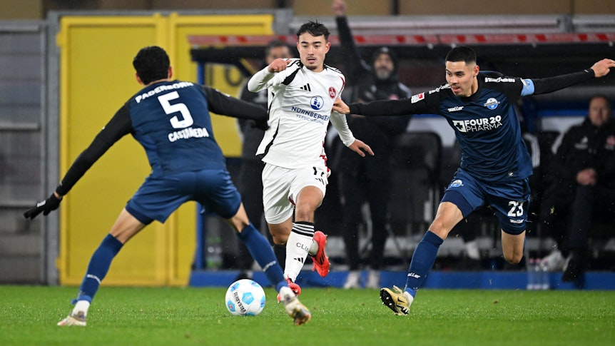 Jens Castrop vom 1. FC Nürnberg führt den Ball im Spiel beim SC Paderborn, Santiago Castaneda und Raphael Obermair versuchen, ihn zu stoppen.